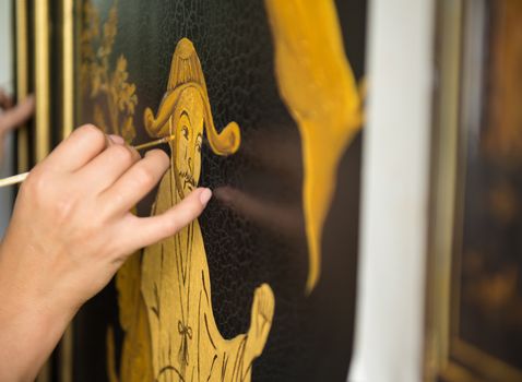 painter decorator draws Chinese pattern of leaves and man, macro shooting