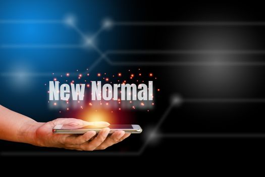 White world new normal on hand holding smartphone with orange light on blue and black technology background. New normal concept.