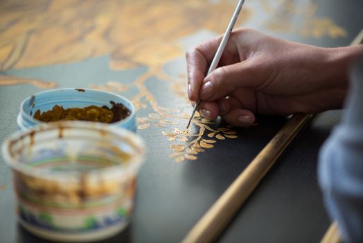 painter decorator draws a pattern of tree and leaves