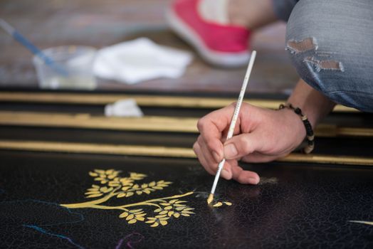 painter decorator draws a pattern of tree and leaves