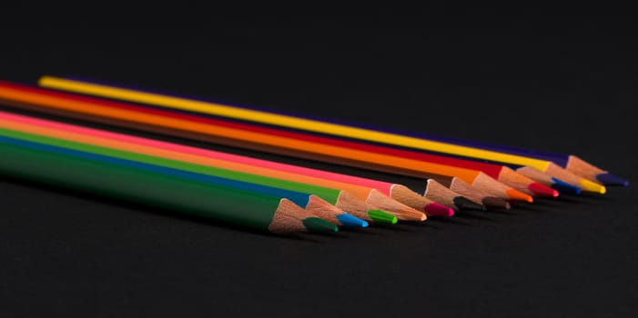 set of colored pencils on a black background isolated. back to school