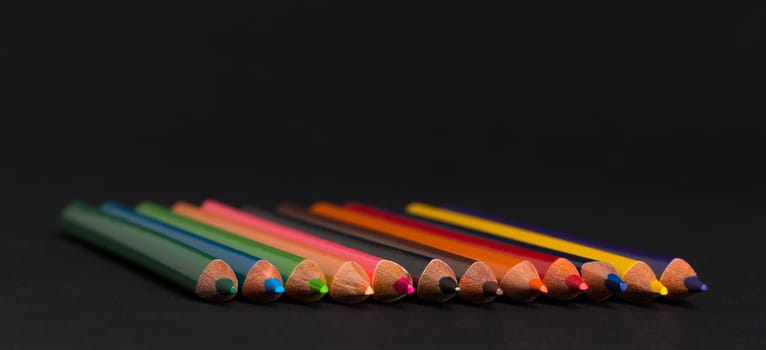 set of colored pencils on a black background isolated. back to school