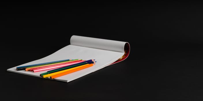 album for drawing and color pencils on a black background, isolated. back to school