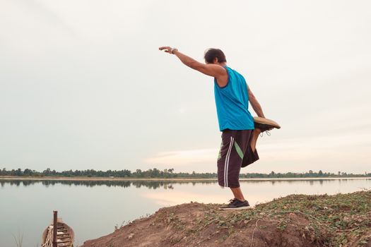 Old men exercise for health by jogging at sunset by the edge of the natural lake, health concept.