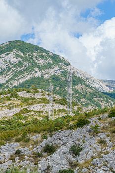 mountainside covered with vegetation and power transmission towers, sunny summer day