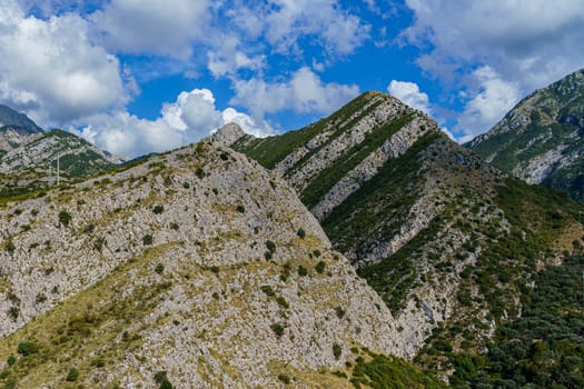 peaks and slopes of mountains covered with vegetation against a blue sky with clouds