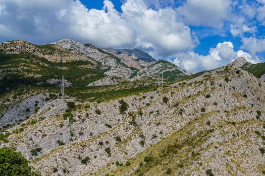 peaks and slopes of mountains covered with vegetation against a blue sky with clouds