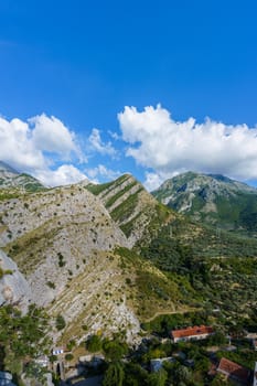 peaks and slopes of mountains covered with vegetation against a blue sky with clouds