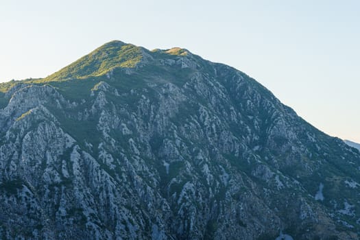 peak and slopes of mountains covered with vegetation against a blue sky 