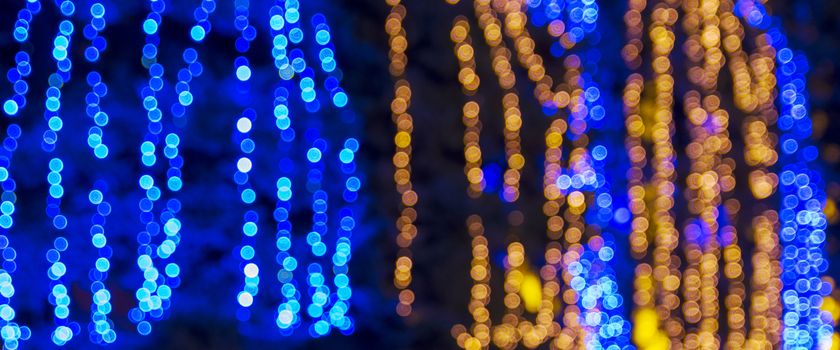 abstract blurred background with round blue and yellow bokeh on a black background, christmas garlands