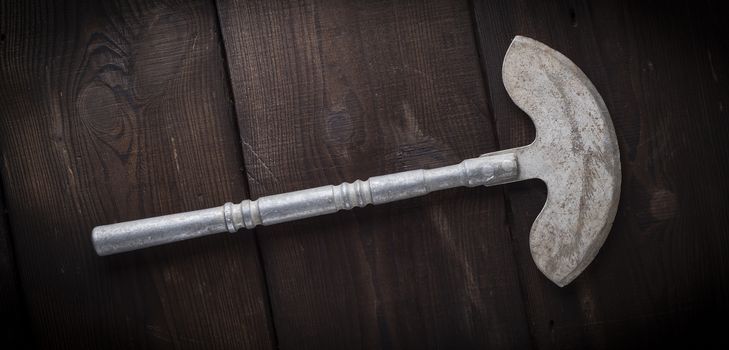 very old iron hatchet for cutting meat or vegetables on brown wooden board, close up