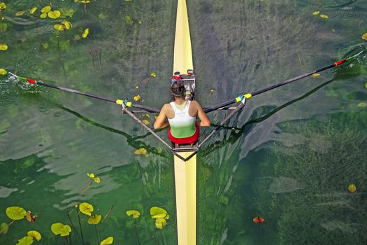 Woman Single sculls rower during the start of a rowing on the tranquil lake
