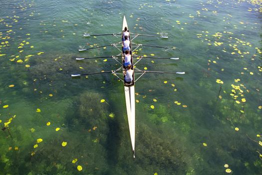Women's quadruple rowing team on turquoise green lake

