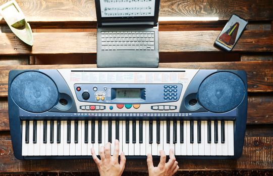 Man playing piano while taking online lessons at home and using a metronome