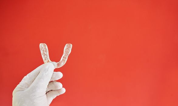 Invisible bracelets on a red background held in one hand by a latex glove