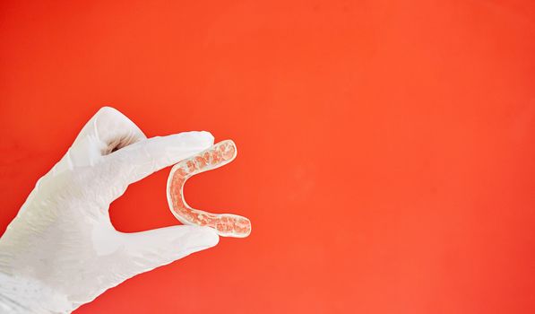 Invisible bracelets on a red background held in one hand by a latex glove