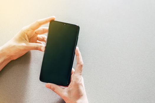 Image of two hands on a table holding a mobile phone