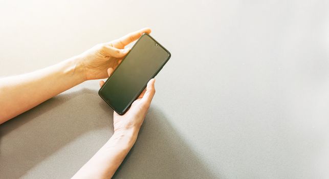 Image of two hands on a table holding a mobile phone