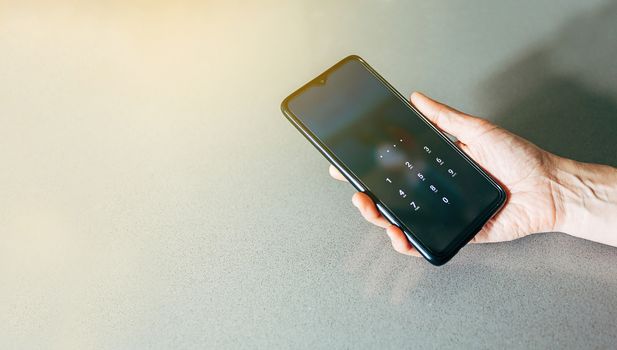 Mobile phone held in one hand and showing the lock screen