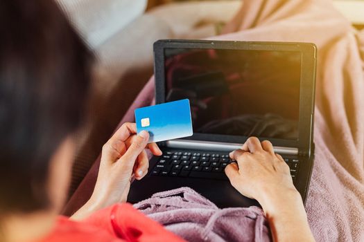 Woman lying on the sofa and shopping online from home with her tablet and credit card