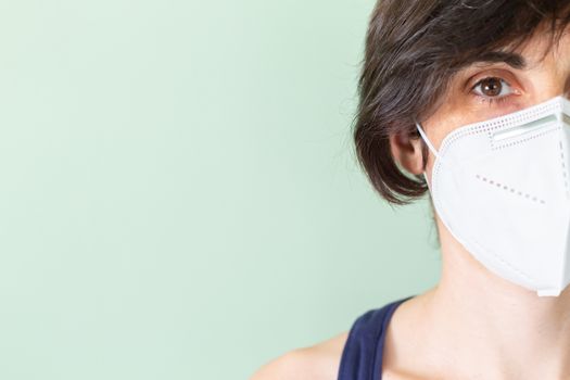 Portrait of a Caucasian woman wearing a protective mask against Coronavirus on a green background