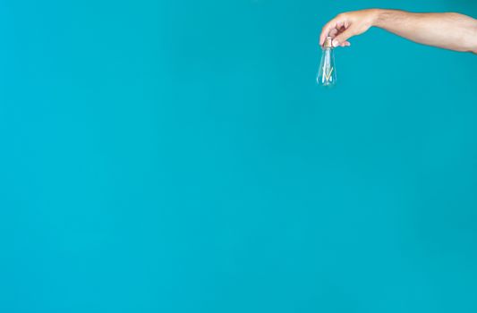 Right hand holding a light bulb on a green background at the top