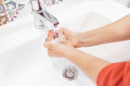 Woman washing her hands hygienically with soap in a sink