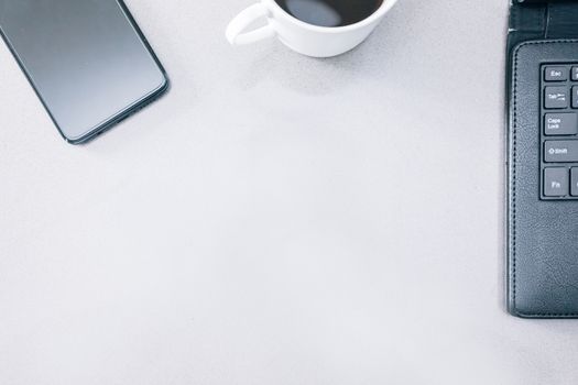 Grey table with a mobile phone, a tablet and a cup of coffee with some copy space