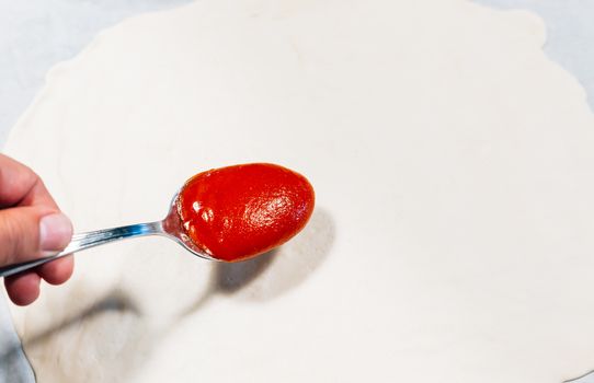 a person putting a tomato on a pizza base