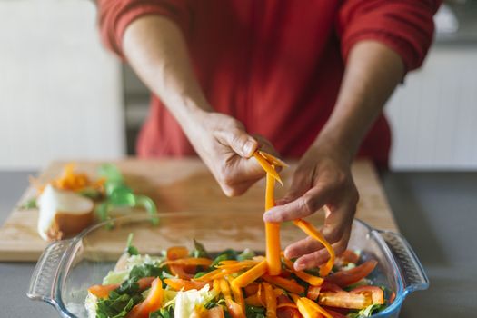 Woman cutting carrots and putting them in a salad with her hands