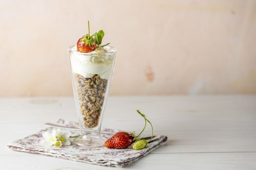 Glass of healthy breakfast with granola and greek yogurt close up. Sweet homemade yogurt with ripe fresh strawberries in a jar.