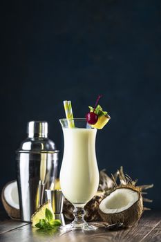 Glass of tasty Frozen Pina Colada Traditional Caribbean cocktail decorated by slice of pineapple and cherry, served on dark wooden background