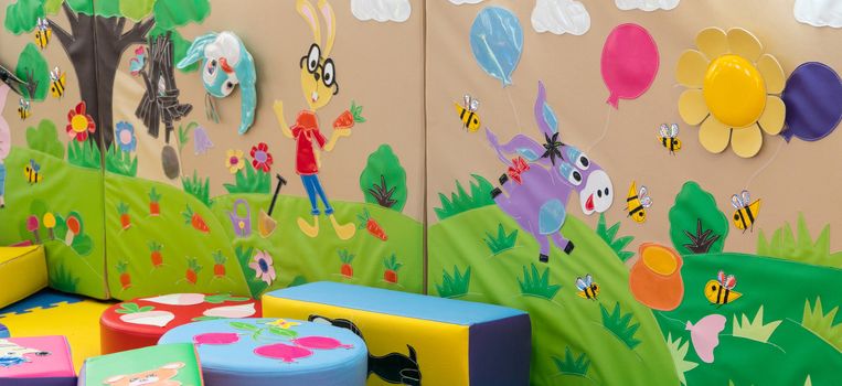colorful children's soft playground, indoors. wall with cartoon characters