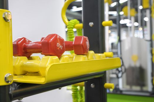 red and yellow sports dumbbells and kettlebells on stand closeup
