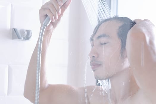 Closeup young man washing hair with with shampoo isolated on white background, vintage tone, selective focus