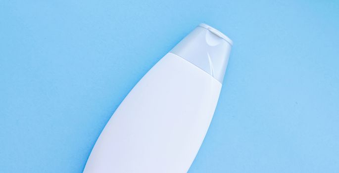 Blank label cosmetic container bottle as product mockup on blue background, hygiene and healthcare
