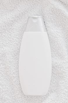 Blank label cosmetic container bottle as product mockup on white towel background, hygiene and healthcare