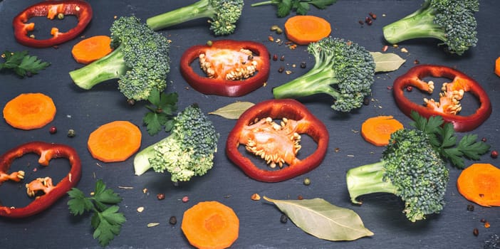 sliced raw slices of vegetables with spices on a black background