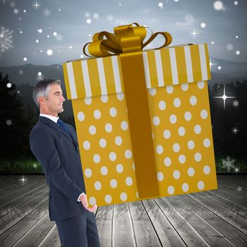 Stylish man with giant gift against wooden planks against mountains