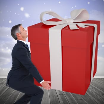 Stylish man with giant gift against clouds in a room