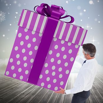 Stylish man with giant gift against clouds on the horizon