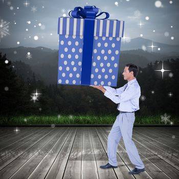 Stylish man with giant gift against wooden planks against mountains