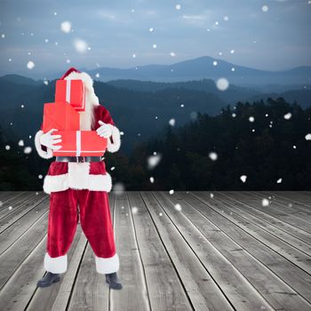 Santa carrying gifts against wooden planks against mountains