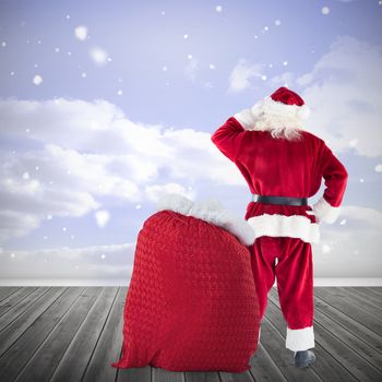 Santa with sack of gifts against clouds in a room