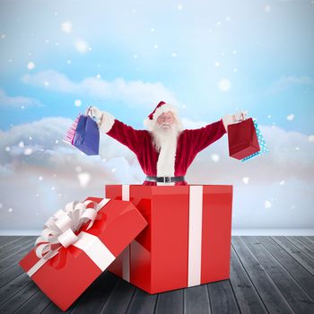 Santa standing in large gift against clouds in a room