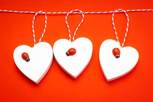 Blank for the designer. Valentines day concept. Greeting card. Copy space.Valentine's Day. White wooden hearts on a red background and red ladybugs.