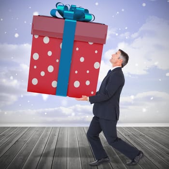 Stylish man with giant gift against clouds in a room