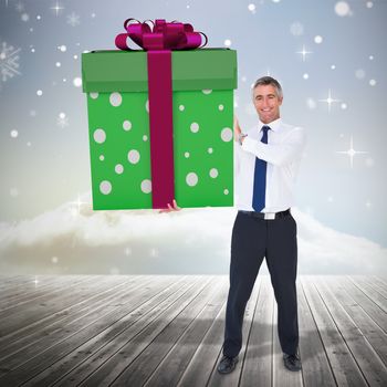 Stylish man with giant gift against clouds on the horizon