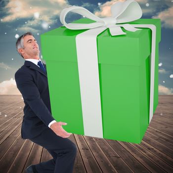 Stylish man with giant gift against wooden planks leading to blue sky