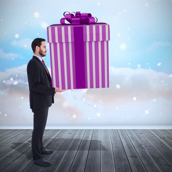 Stylish man with giant gift against clouds in a room